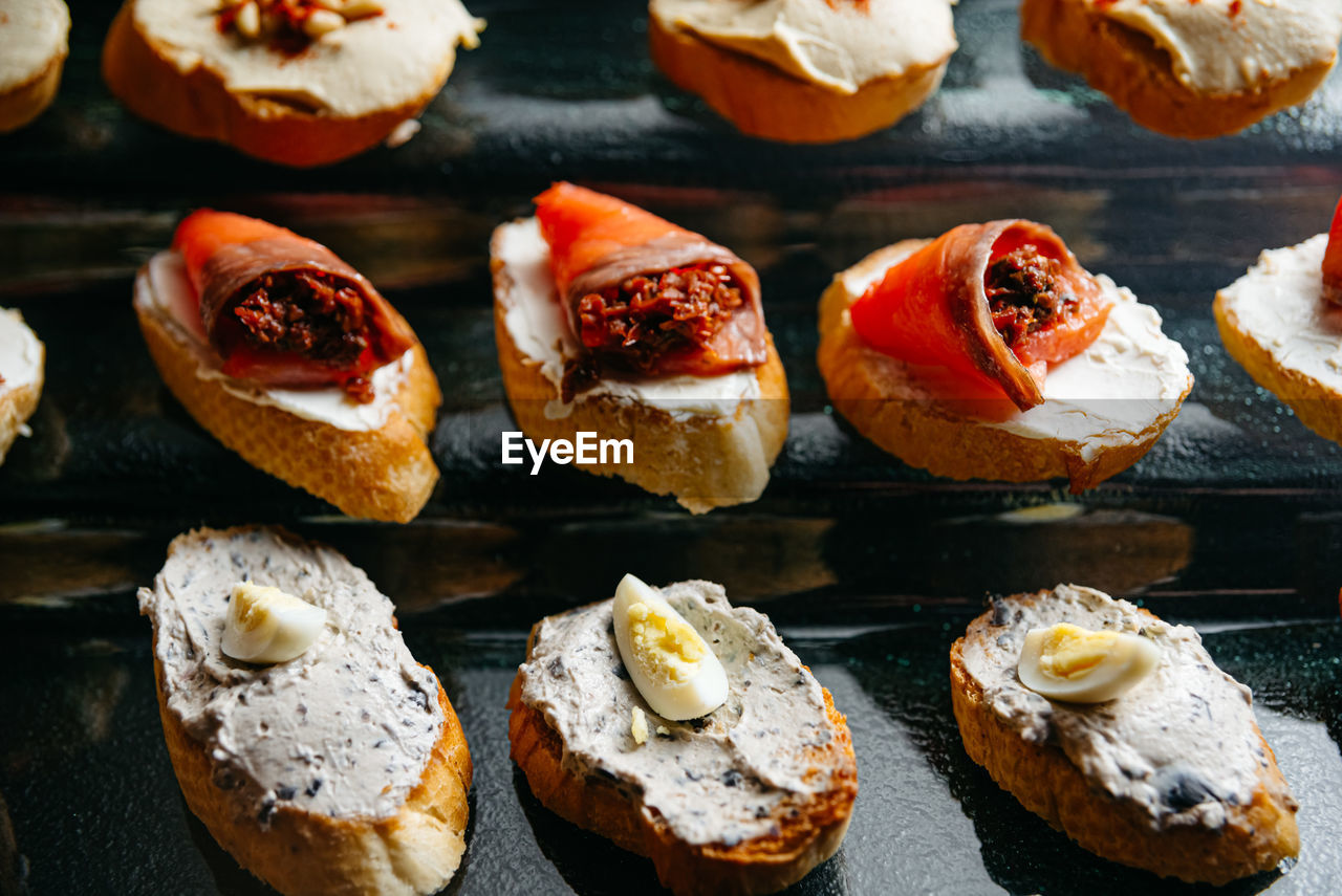 A close up of a bunch of appetizers on a glass stand. crostini with salmon fillet.