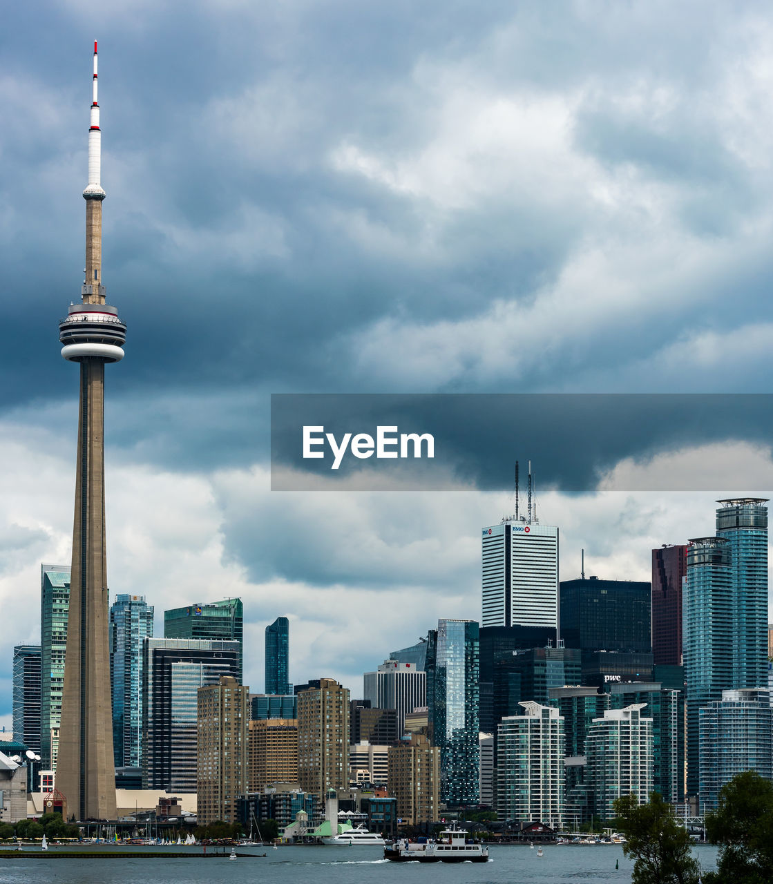 Communications tower in city against cloudy sky