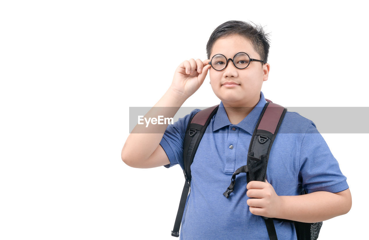 PORTRAIT OF YOUNG MAN STANDING AGAINST GRAY BACKGROUND