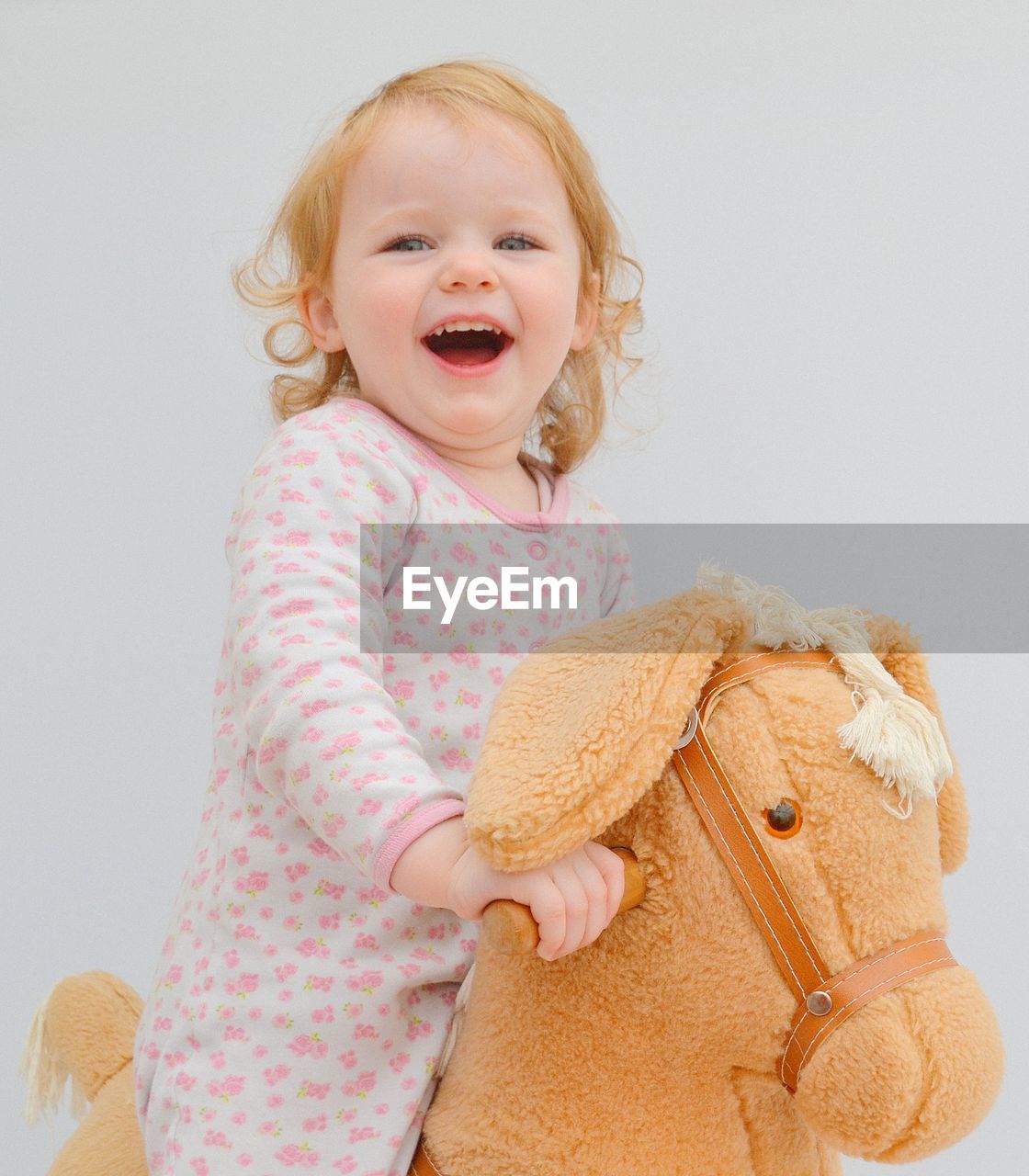 Portrait of smiling girl sitting on stuffed toy against white background