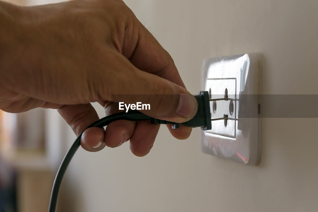 Cropped hand of person plugging electric switch