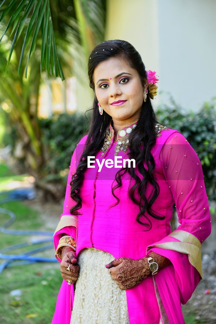 Portrait of smiling bride in traditional clothing standing outdoors