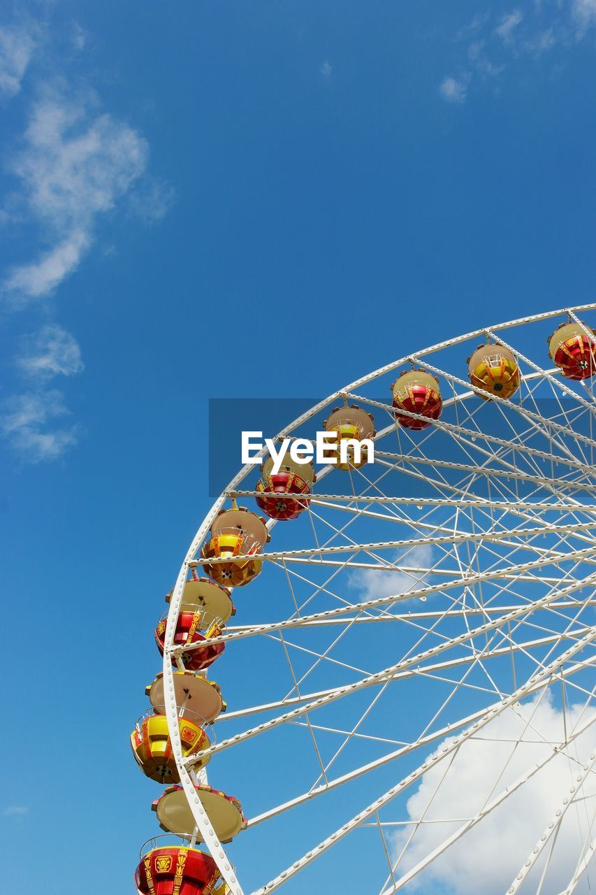 Low angle view of cropped ferris wheel against blue sky