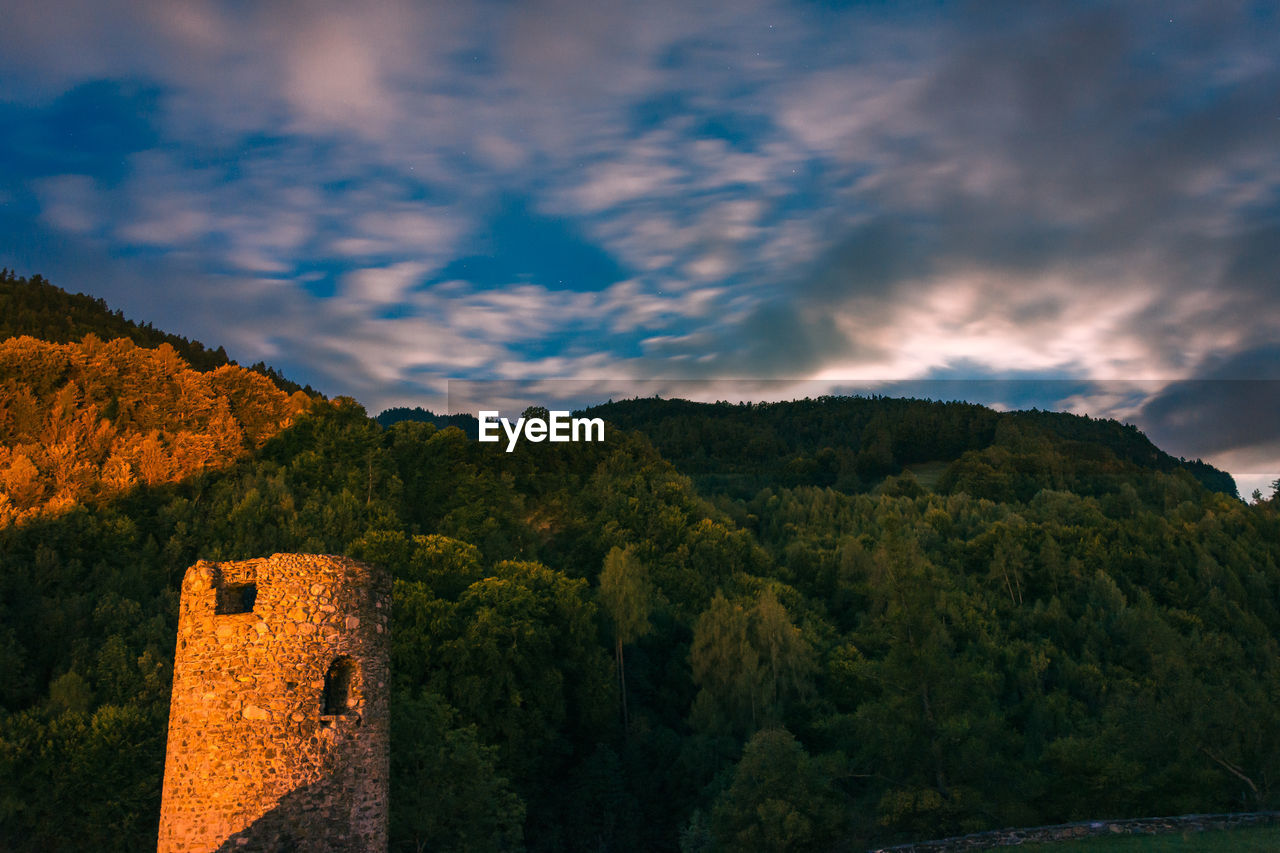 SCENIC VIEW OF TREES AND MOUNTAINS AGAINST SKY DURING SUNSET