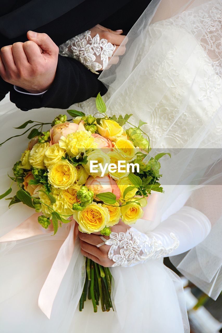 HIGH ANGLE VIEW OF WOMAN HOLDING BOUQUET OF PEOPLE ON WHITE WALL