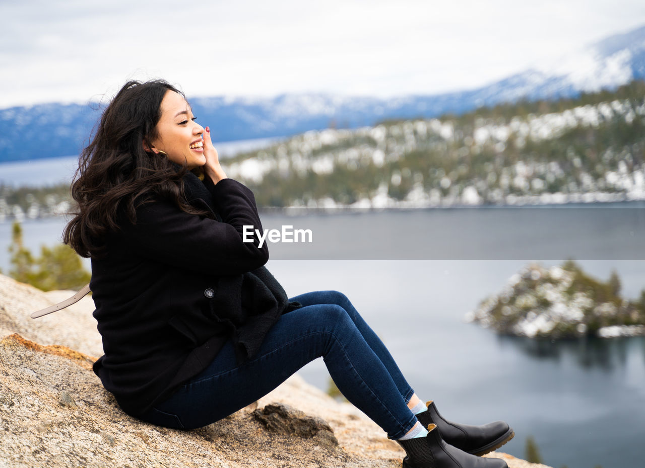 Young woman looking away while sitting on rock