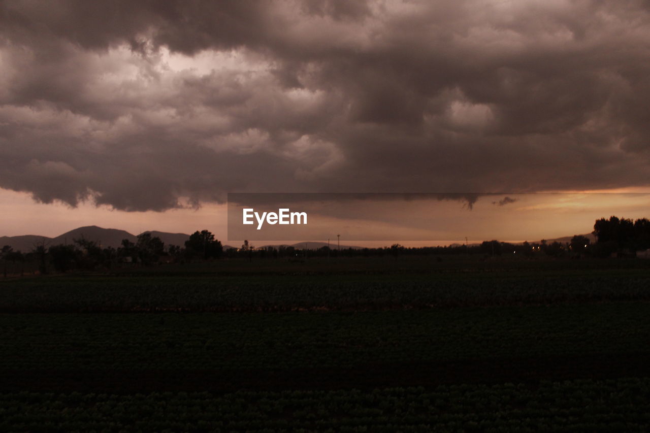SCENIC VIEW OF LANDSCAPE AGAINST CLOUDY SKY AT SUNSET
