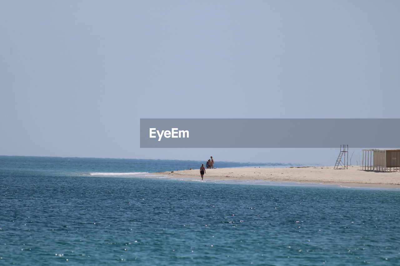 water, sea, ocean, sky, horizon, shore, coast, beach, nature, land, horizon over water, scenics - nature, beauty in nature, body of water, clear sky, wave, day, copy space, blue, holiday, bay, one person, tranquility, vacation, outdoors, travel, trip, tranquil scene, wind wave, sunny, travel destinations, men, lifestyles, architecture, waterfront, leisure activity, idyllic, tourism
