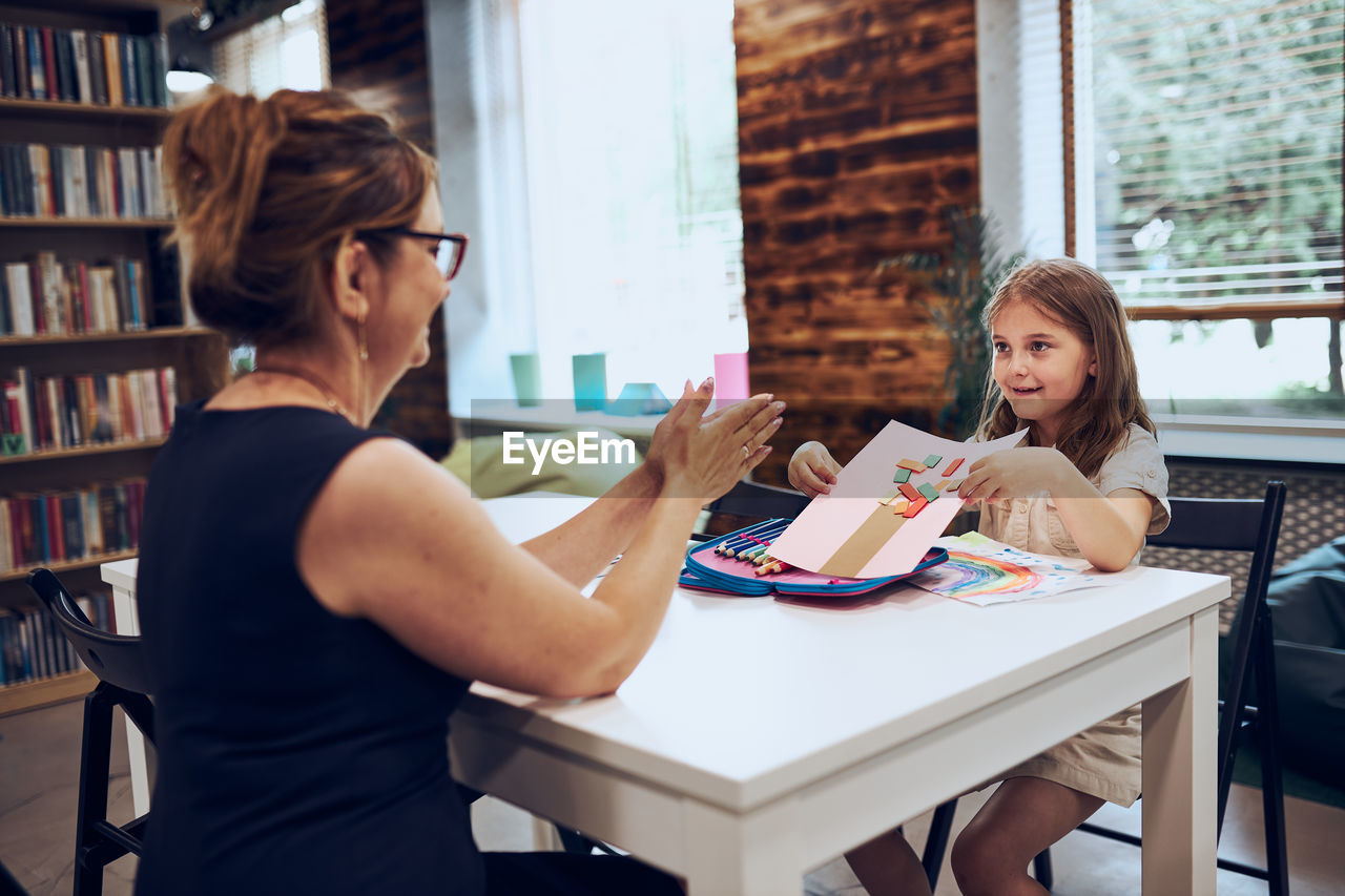 Teacher assisting schoolgirl during art class. child doing homework. primary school. learn and fun