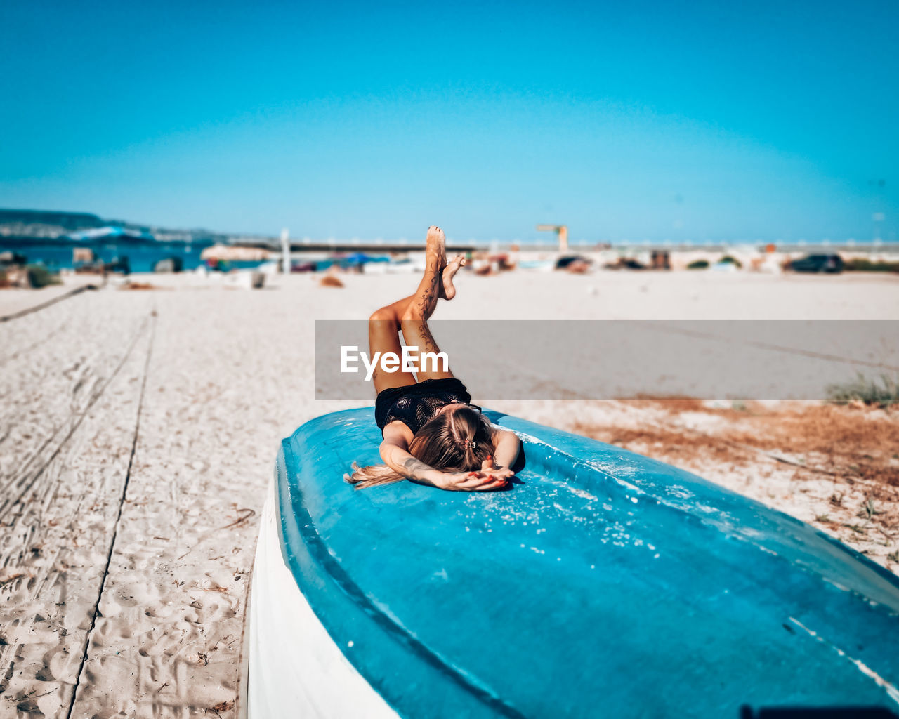 Woman relaxing on beach against blue sky