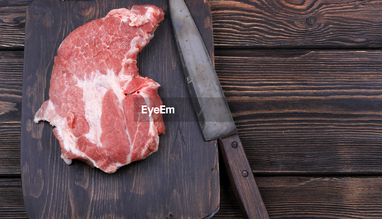 Chopping cutting board with meat and a knife for slicing on the old wooden background with space 