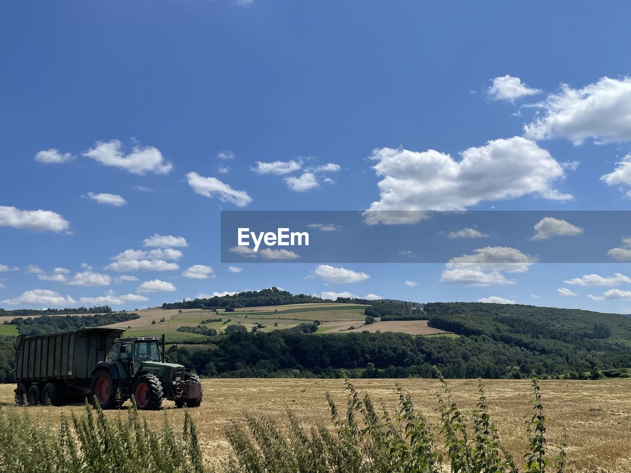 landscape, field, sky, agriculture, land, environment, rural scene, rural area, plant, cloud, nature, grass, transportation, farm, prairie, grassland, plain, mode of transportation, crop, horizon, land vehicle, scenics - nature, blue, meadow, hill, agricultural equipment, tractor, agricultural machinery, day, pasture, growth, harvesting, beauty in nature, food, no people, food and drink, vehicle, outdoors, machinery, tree, travel, cereal plant, non-urban scene, sunlight
