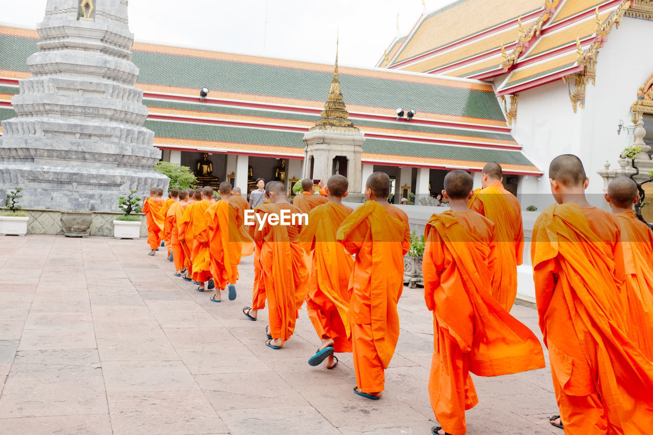 REAR VIEW OF PEOPLE WALKING OUTSIDE TEMPLE