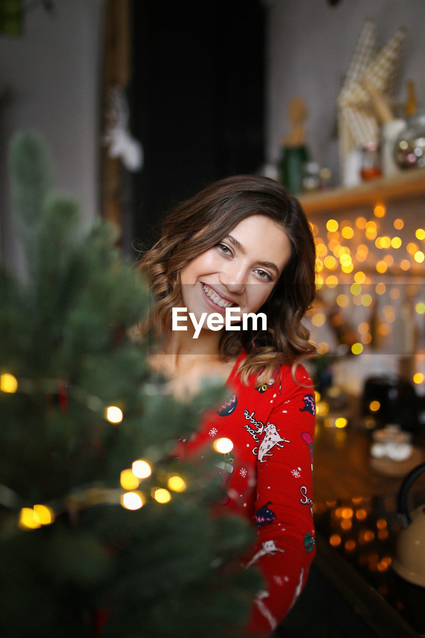 Funny pretty girl in red pajamas having fun on christmas holiday in a cozy indoor house