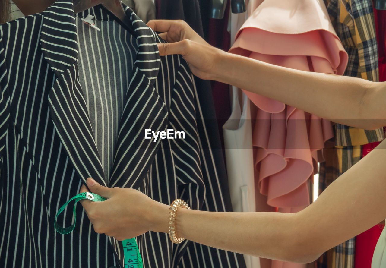 Midsection of woman holding blazer at clothing store