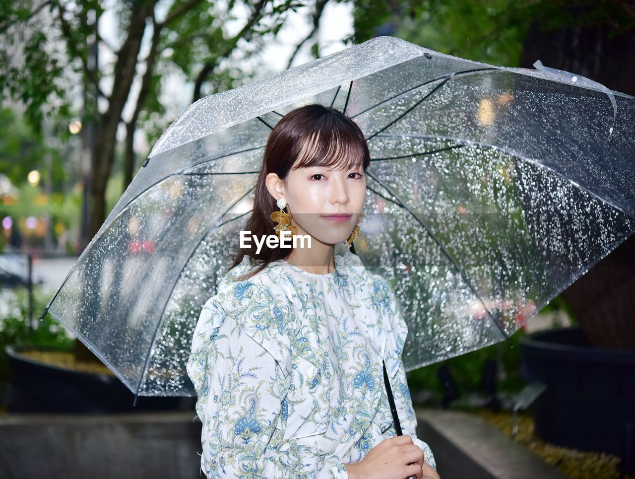 Portrait of woman with umbrella standing in rain during rainy season