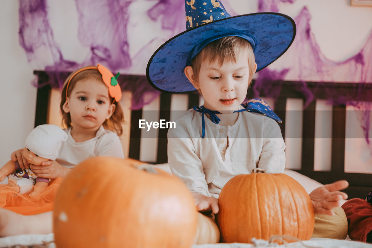 Two little kids in festive halloween costumes with pumpkins having fun. family 