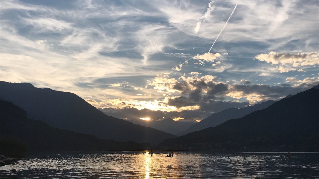 Scenic view of lake by silhouette mountains against sky