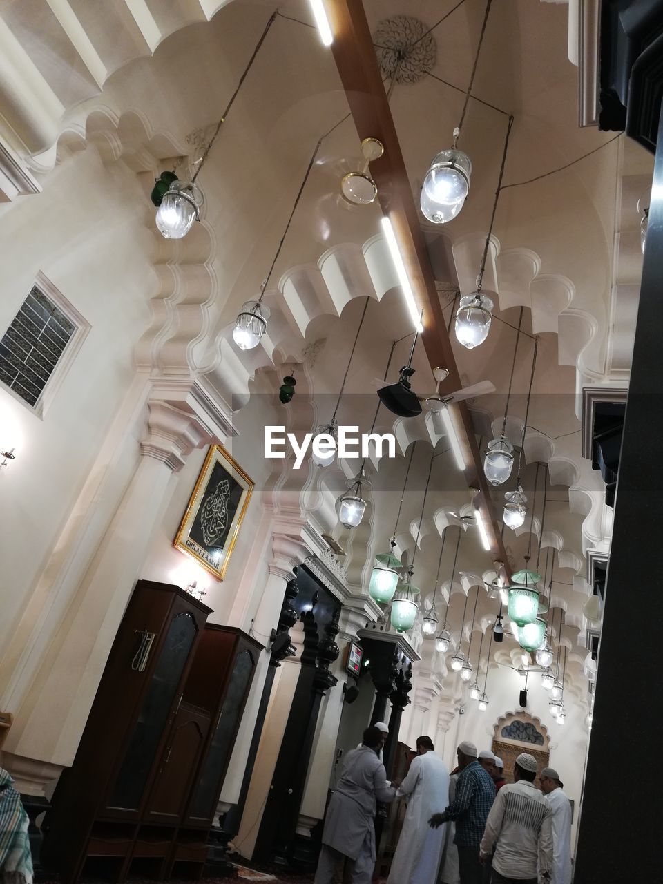 LOW ANGLE VIEW OF ILLUMINATED CHANDELIER HANGING AT HOME