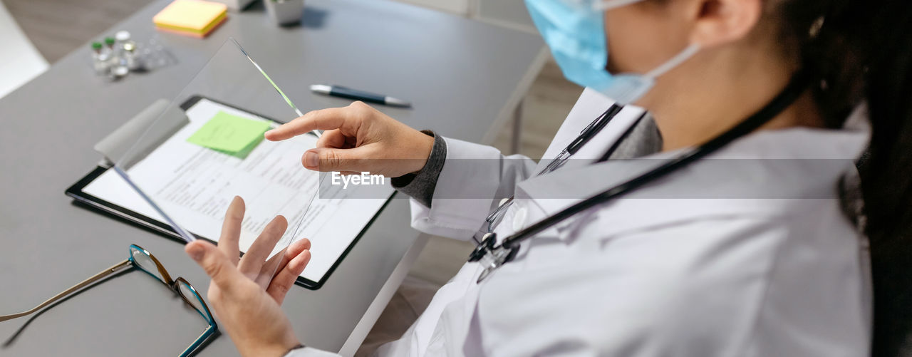 Female doctor working with transparent tablet in her office