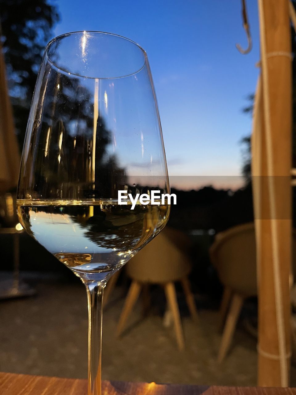 CLOSE-UP OF WINE GLASS ON TABLE AGAINST SKY