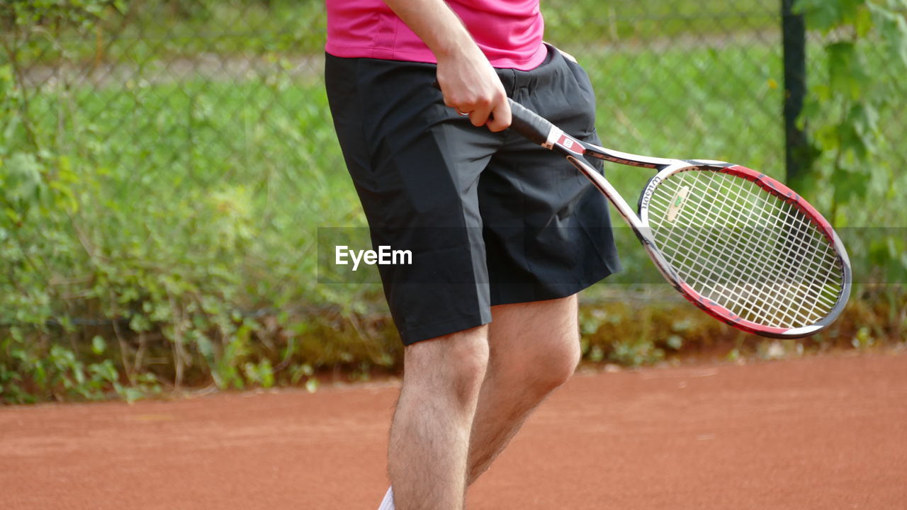 Midsection of man playing badminton in court