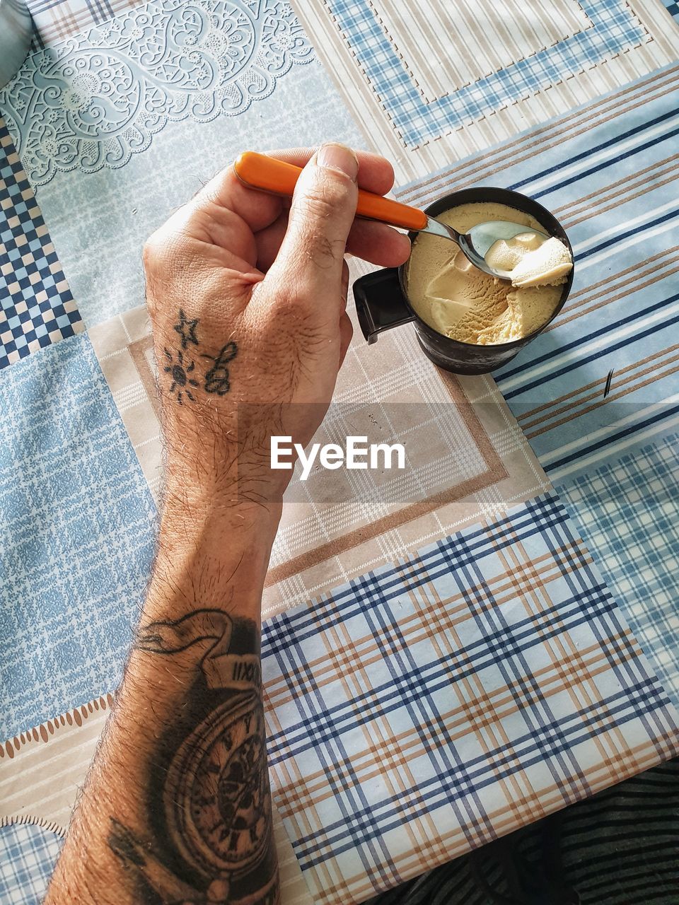 Close-up of hand eating ice cream with spoon on table