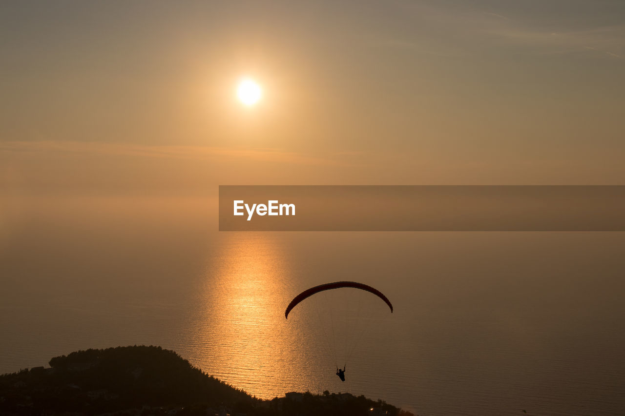 Parachutist against sky during sunset