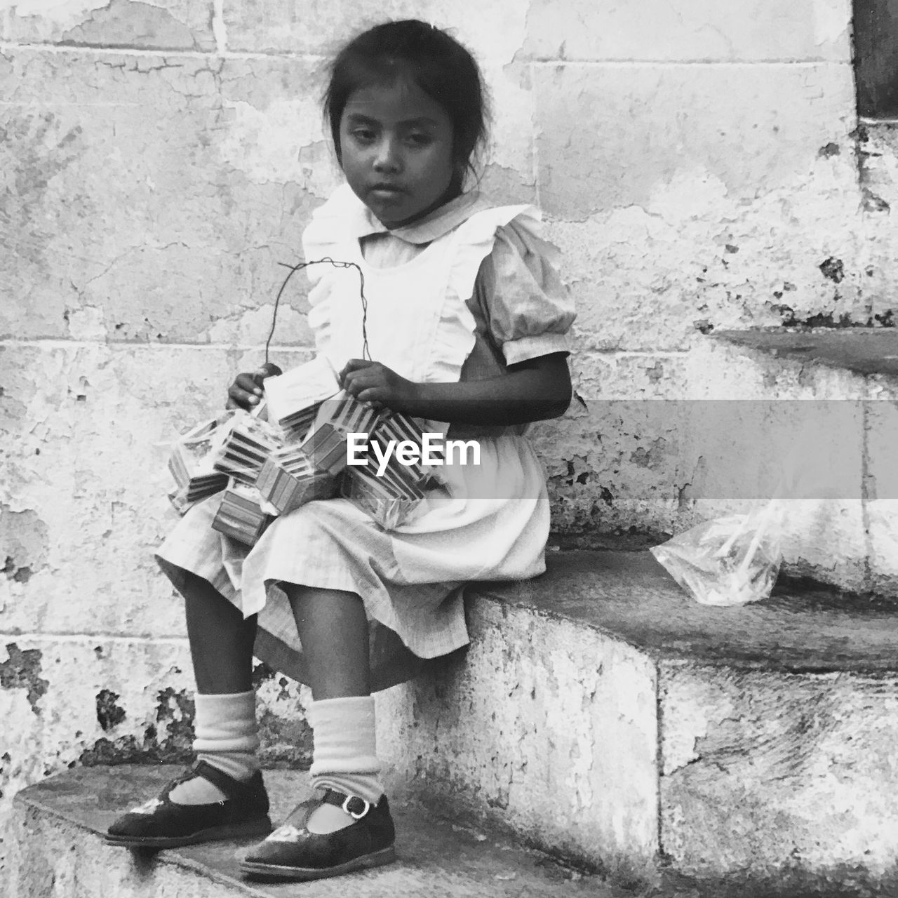PORTRAIT OF HAPPY GIRL SITTING ON WALL