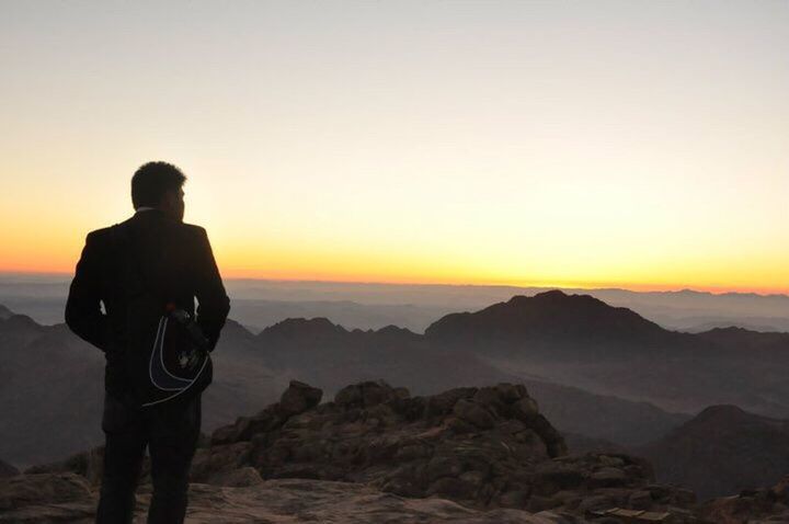 SILHOUETTE PERSON STANDING ON MOUNTAIN DURING SUNSET