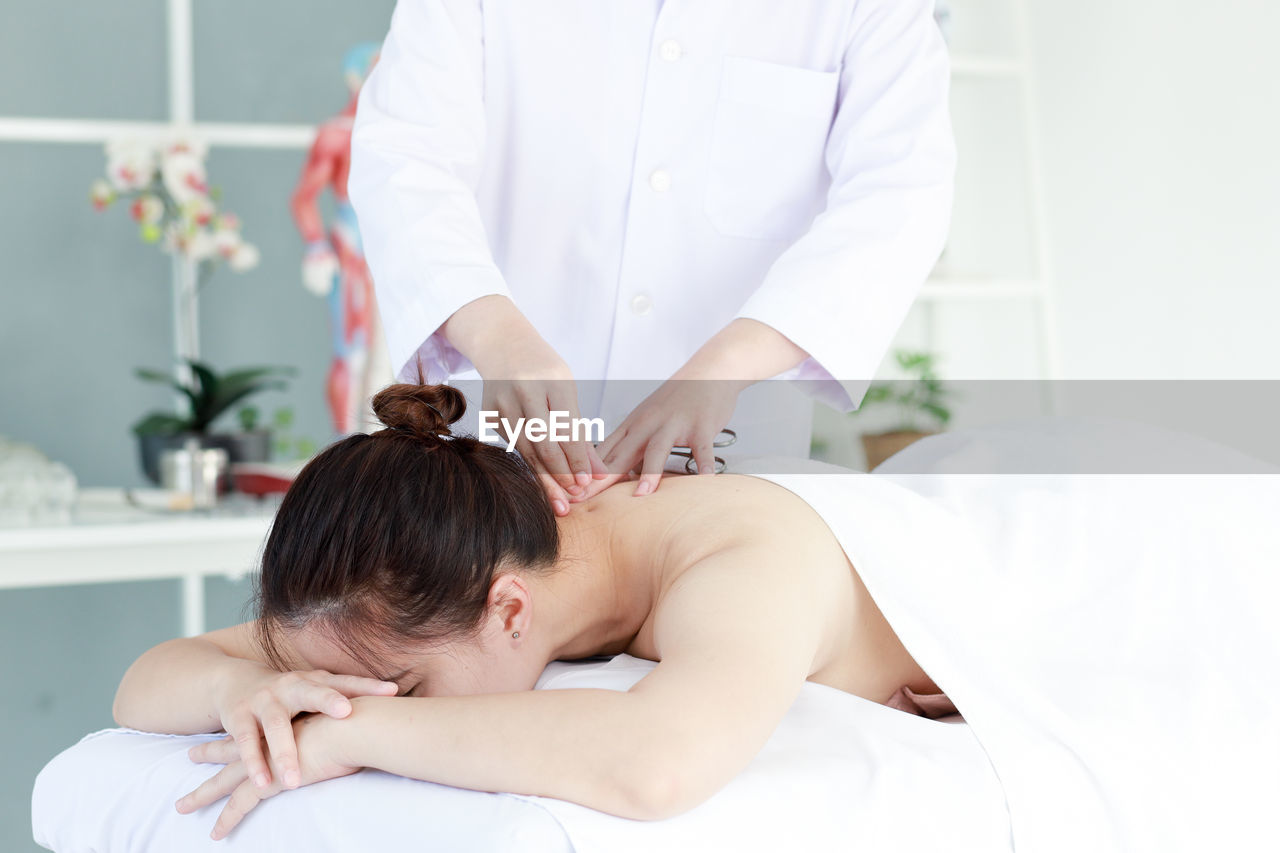 Midsection of doctor treating patient with acupuncture therapy in clinic