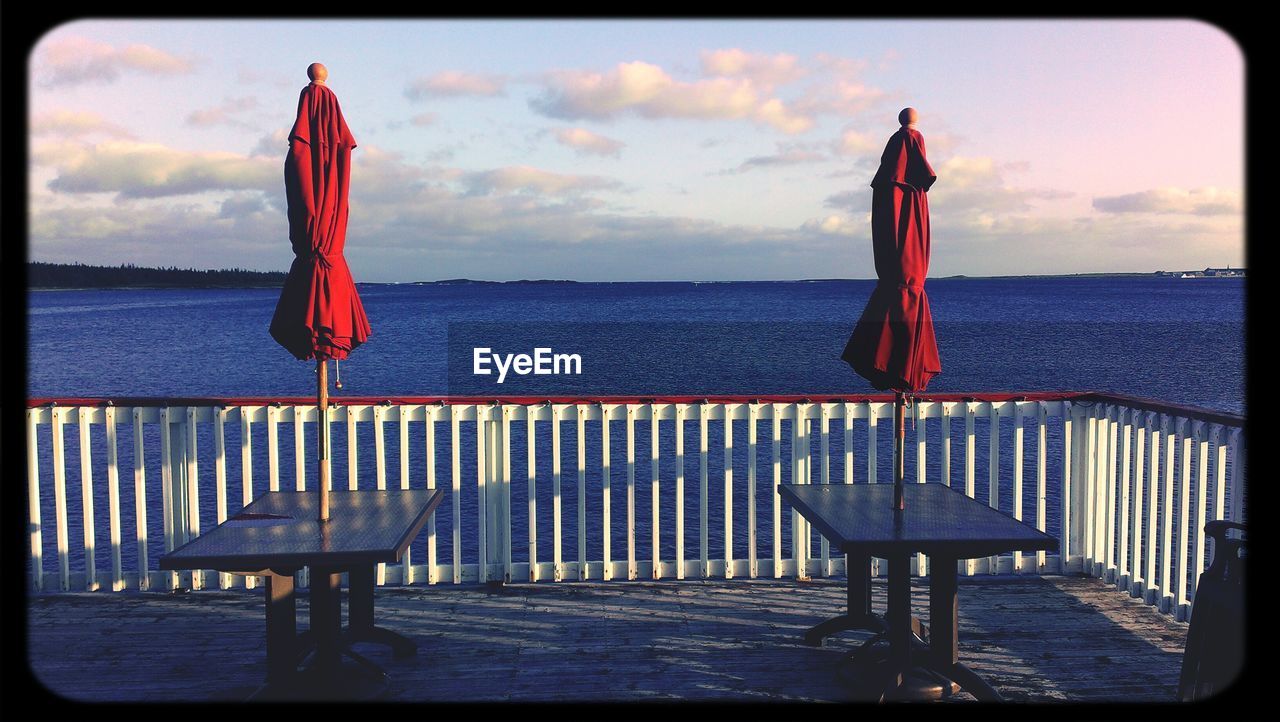 Closed parasols and table on floor against sea