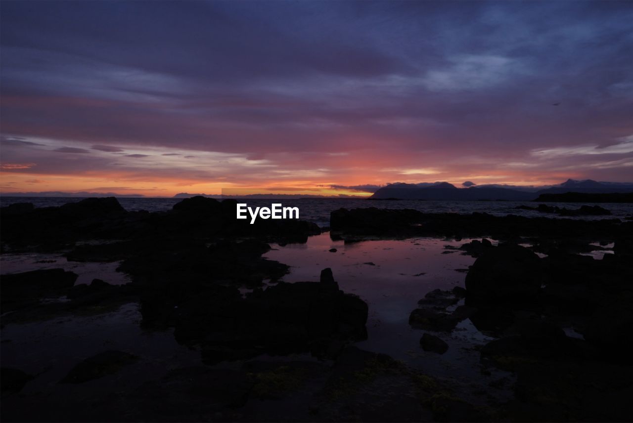 sky, water, cloud, sunset, beauty in nature, dawn, scenics - nature, nature, reflection, sea, environment, rock, landscape, tranquility, land, dramatic sky, evening, horizon, coast, no people, beach, silhouette, afterglow, outdoors, tranquil scene, travel destinations, ocean, night, travel, orange color