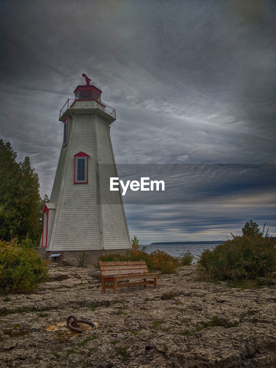 Lighthouse by building against sky