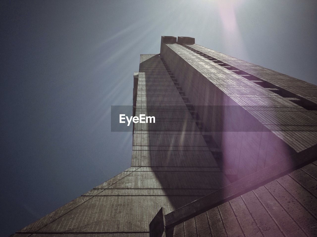 Low angle view of skyscraper against clear sky on sunny day