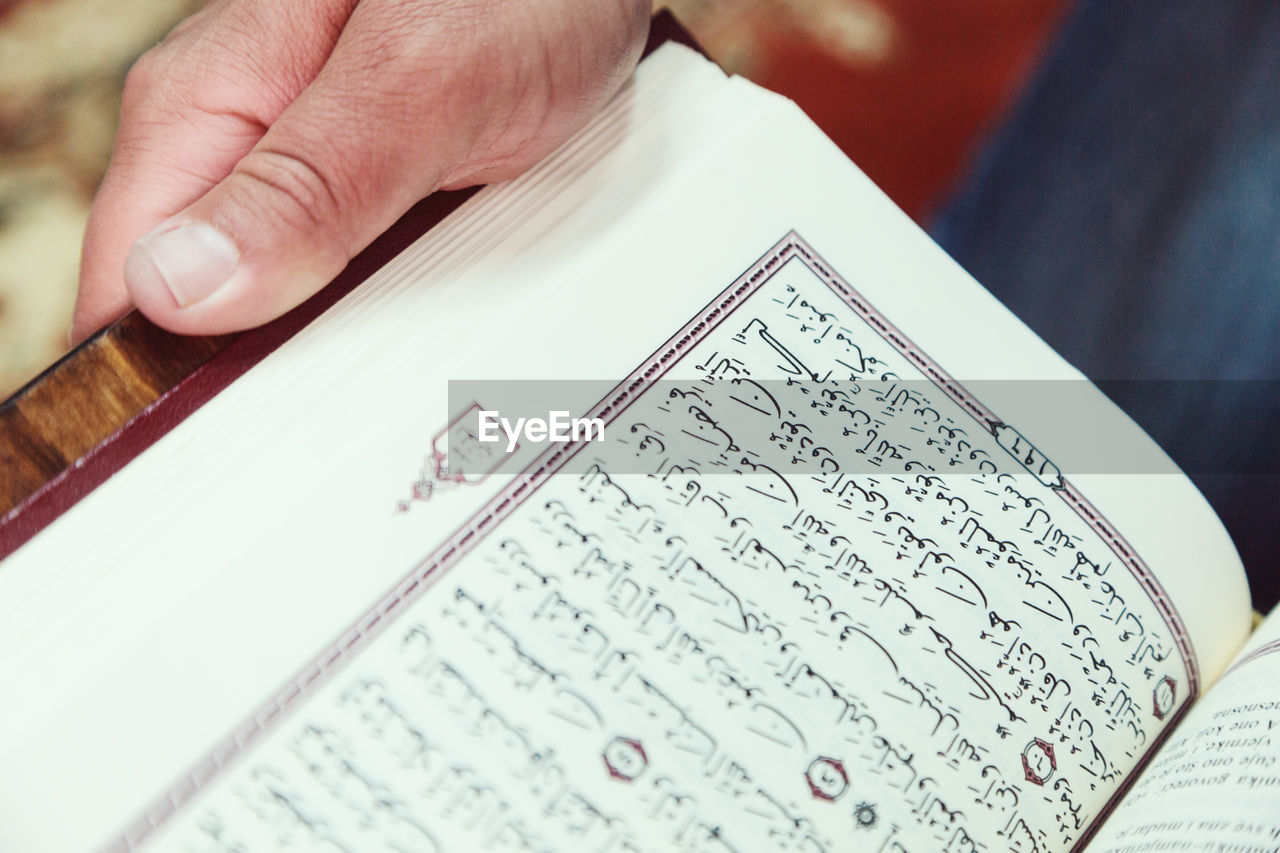 Cropped hands of man reading koran in mosque