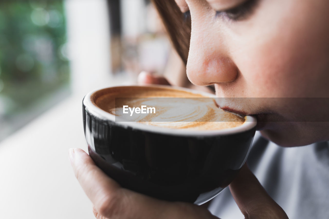Close-up of woman drinking coffee at cafe