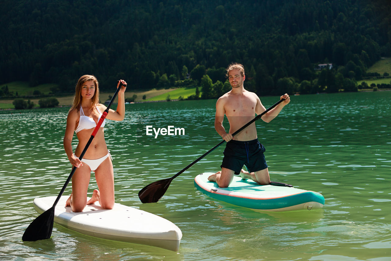 Couple paddleboarding on lake