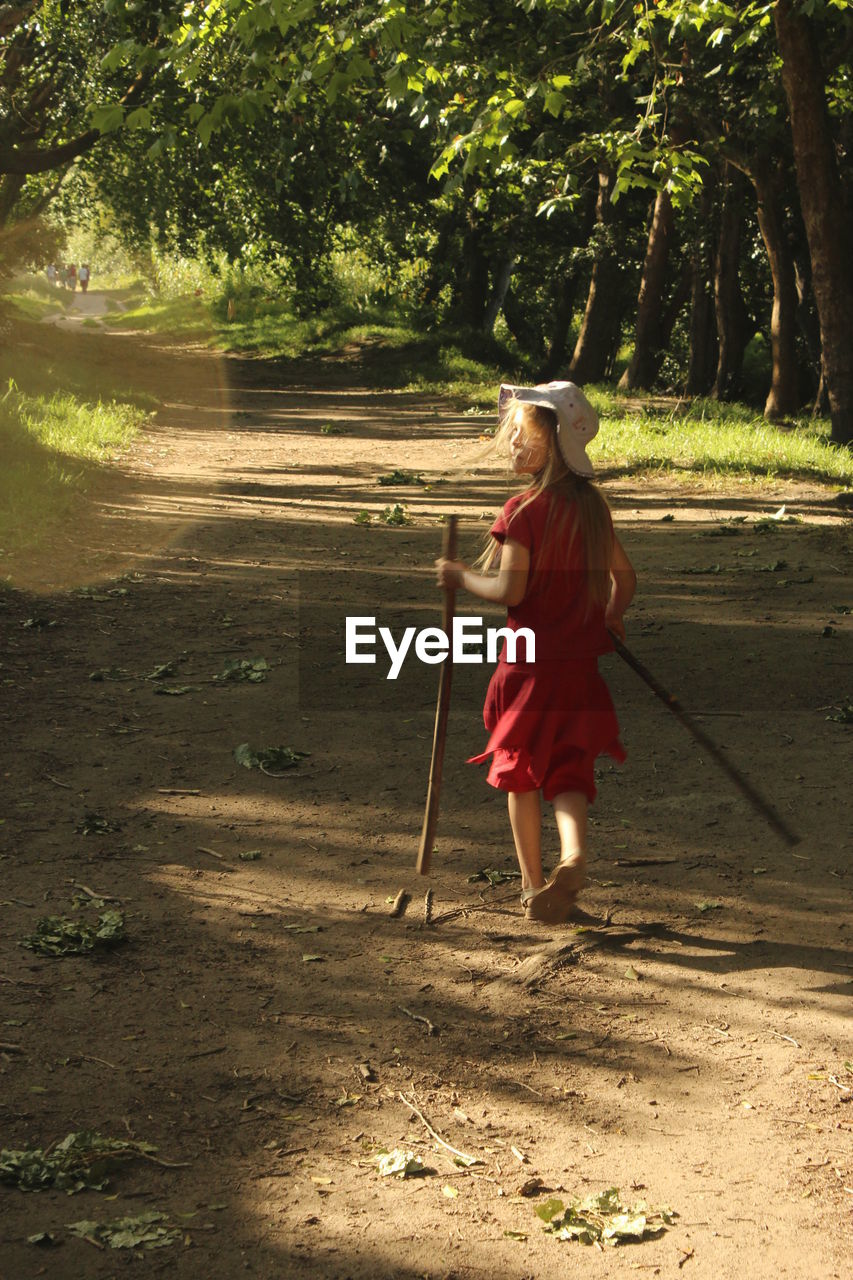 Rear view of girl walking on footpath amidst trees