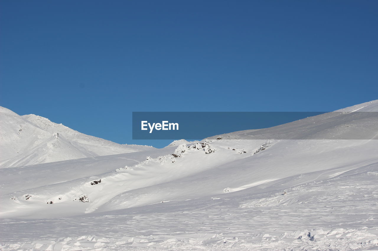 Scenic view of snowcapped mountains against clear blue sky