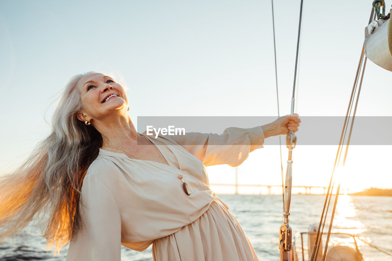 Senior woman standing at sailboat in sea