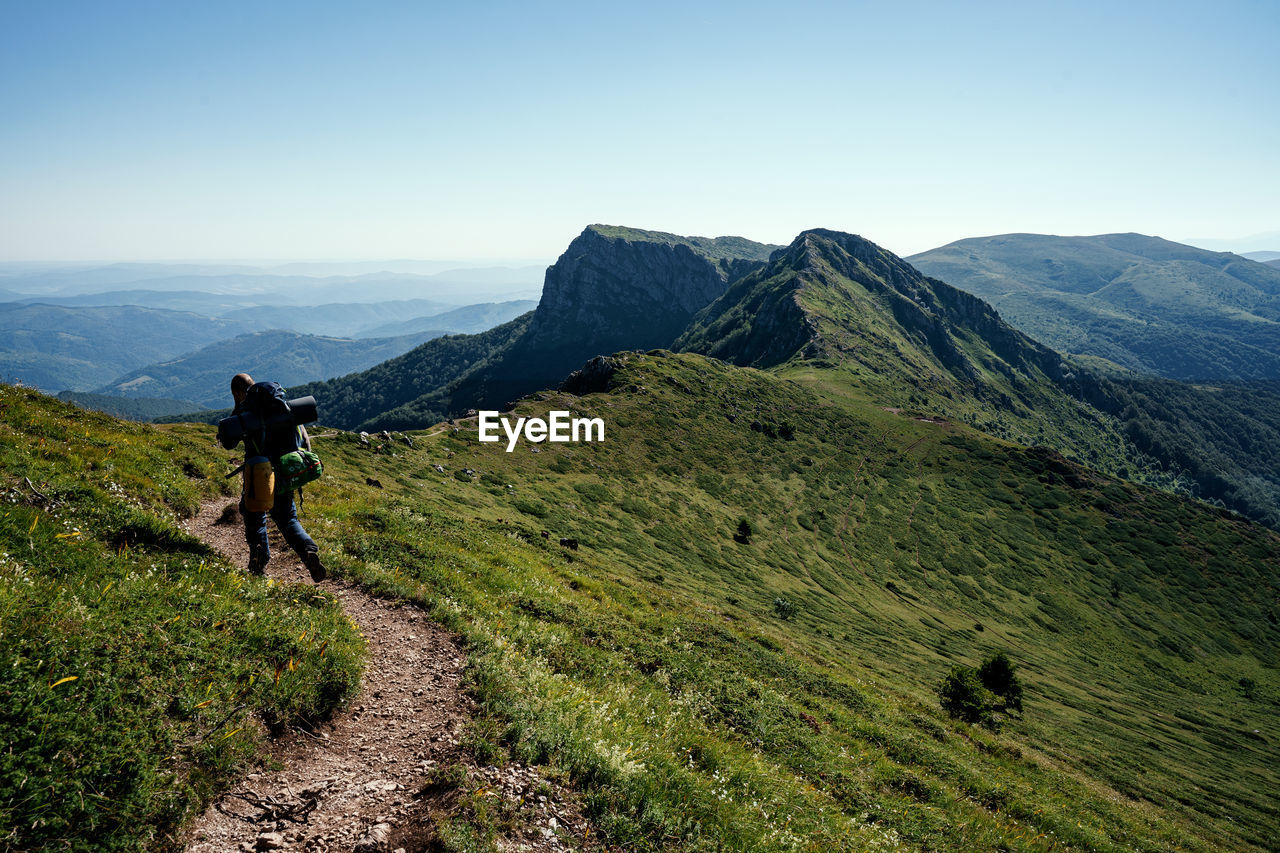 Rear view of man walking on mountain against clear sky. shot in stara planina, bulgaria.