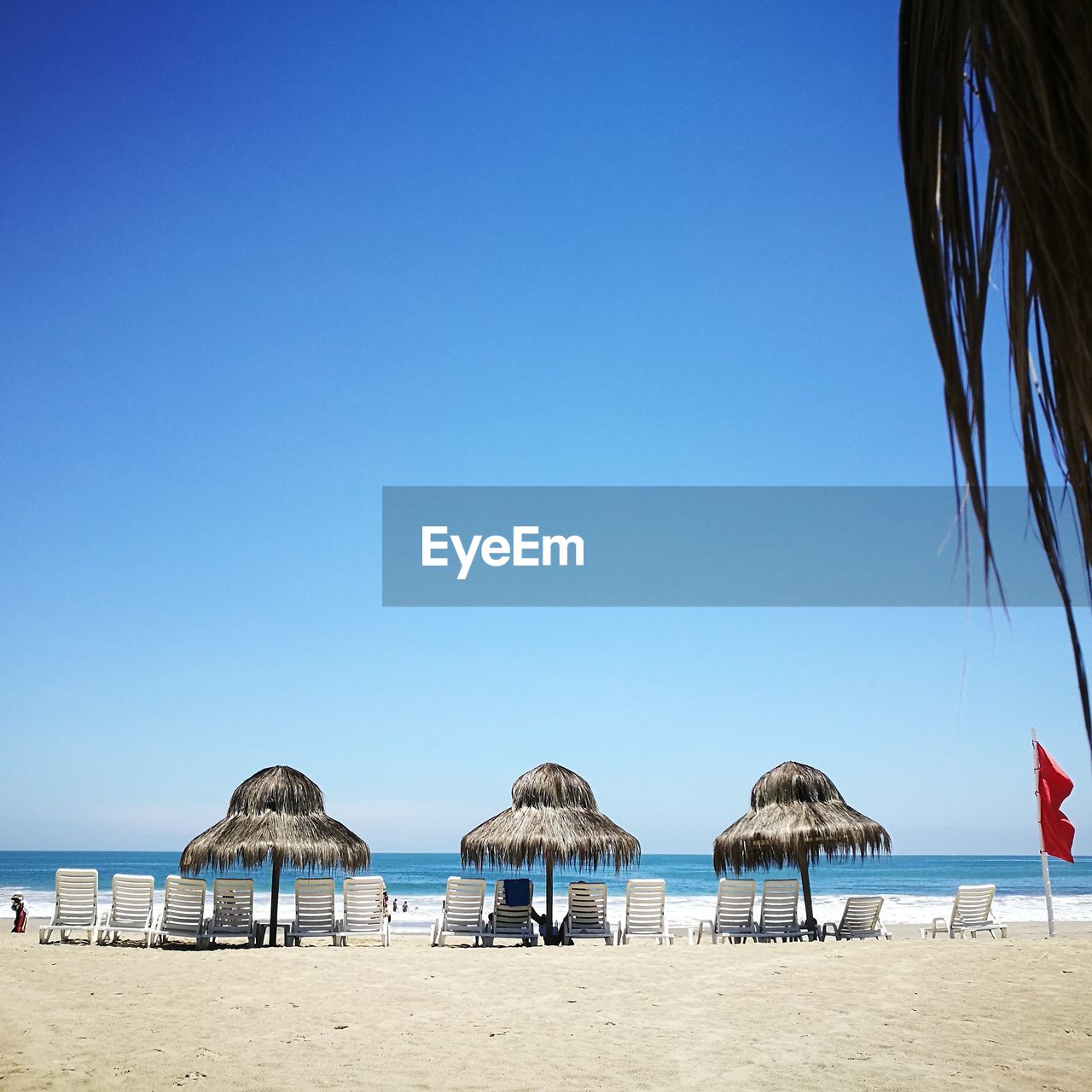 Parasols on beach against clear blue sky