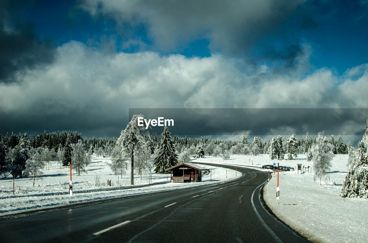 Road by snow covered landscape against sky