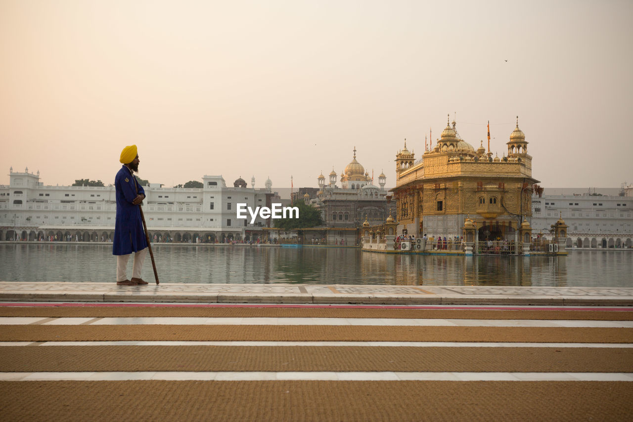 WOMAN STANDING OUTSIDE CATHEDRAL AGAINST SKY