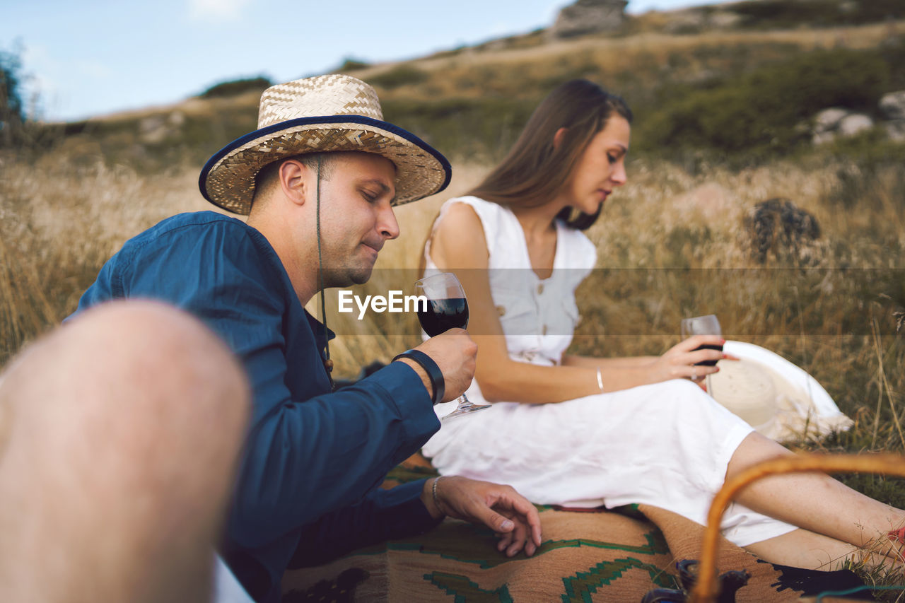 Couple drinking wine while sitting on land