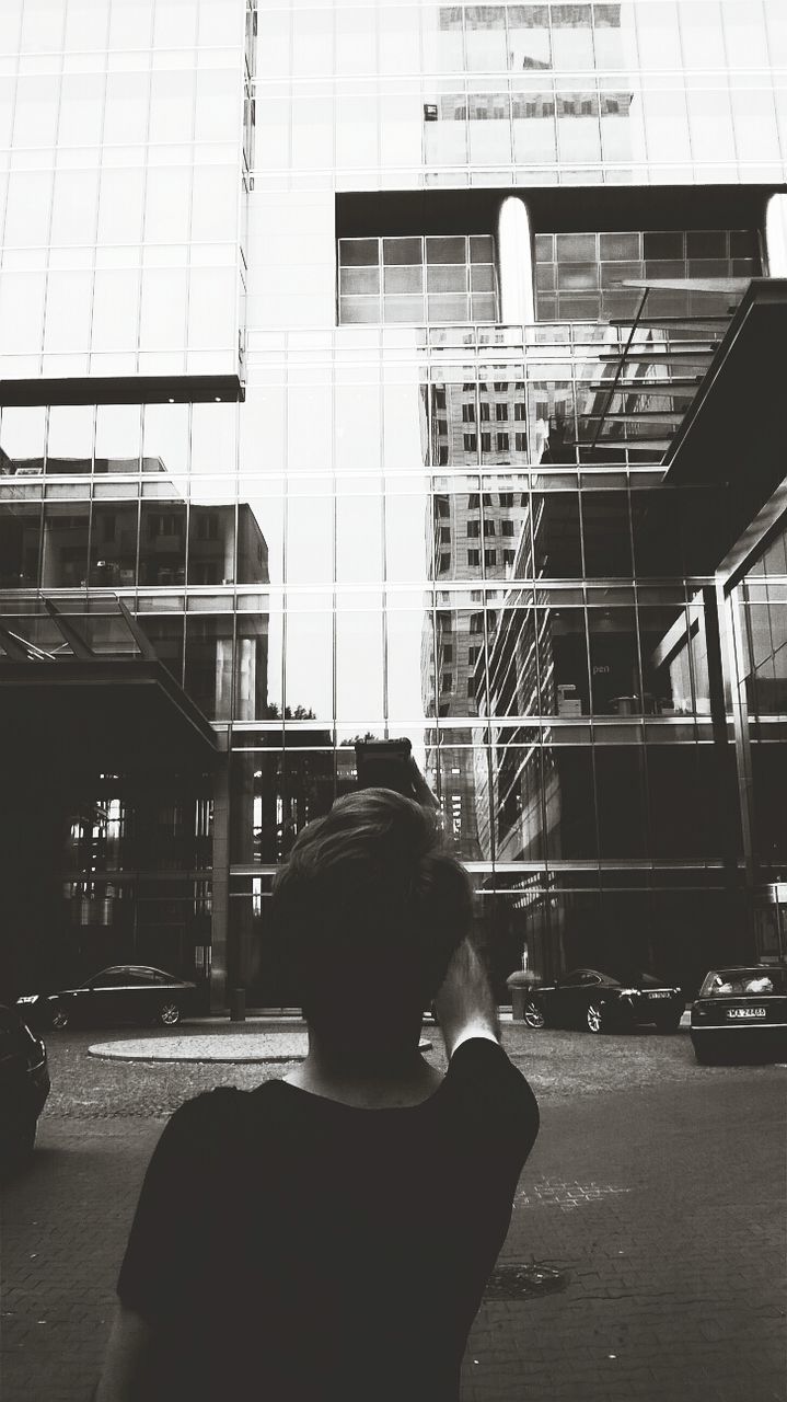 Rear view of man photographing modern building
