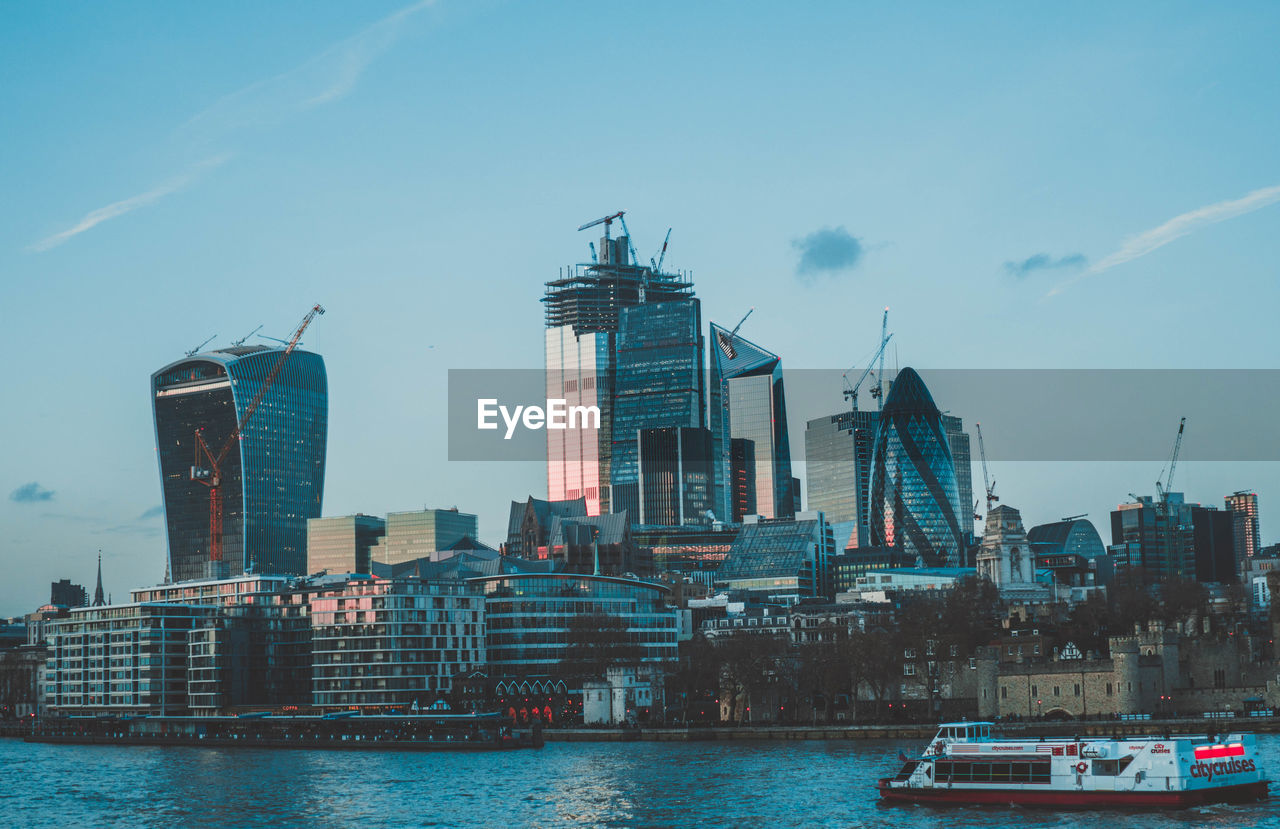 BUILDINGS BY RIVER AGAINST SKY