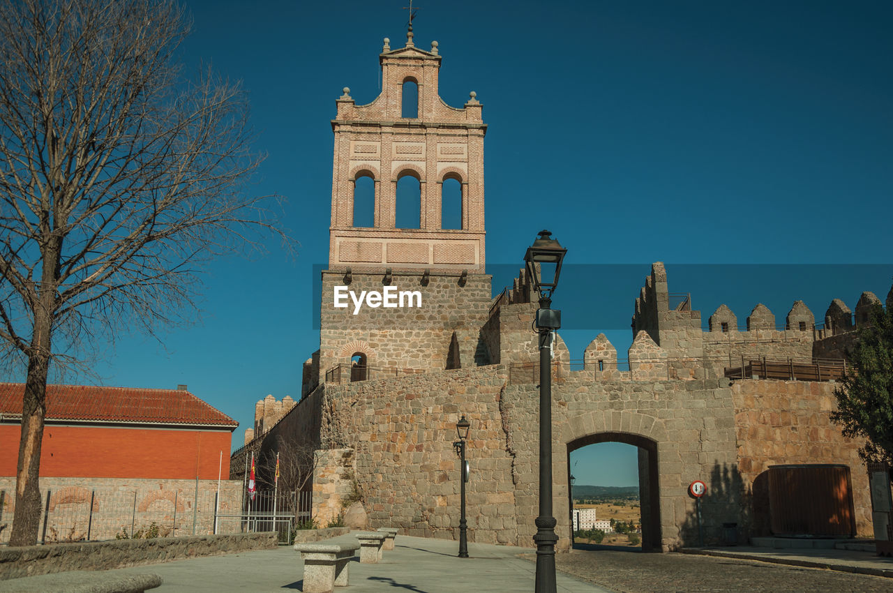 Street going through the carmen gateway on the stone city wall and brick tower in avila, spain.