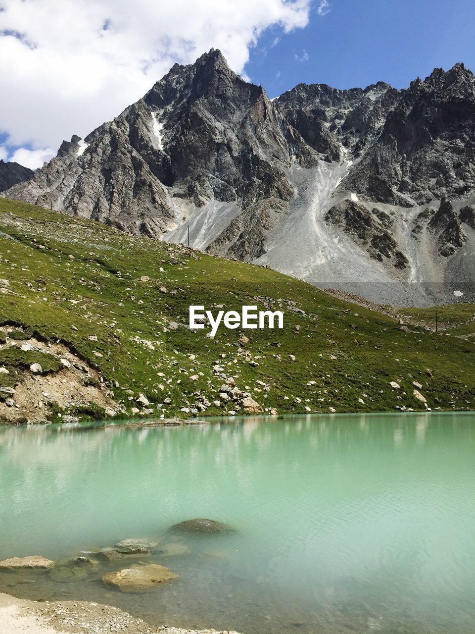 Scenic view of lake and rocky mountains against sky on sunny day